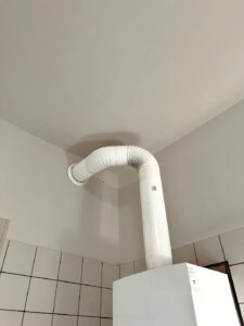 Weisses Abgasrohr einer Heizwerttherme welches bis zum Rauchfang führt